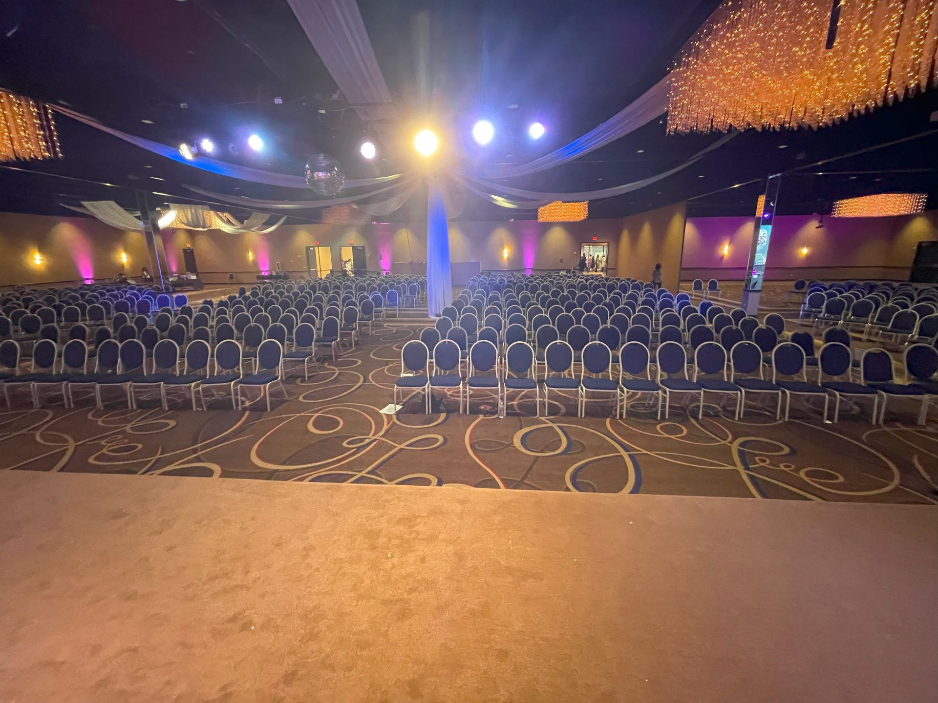 A large empty auditorium with rows of chairs and a stage.