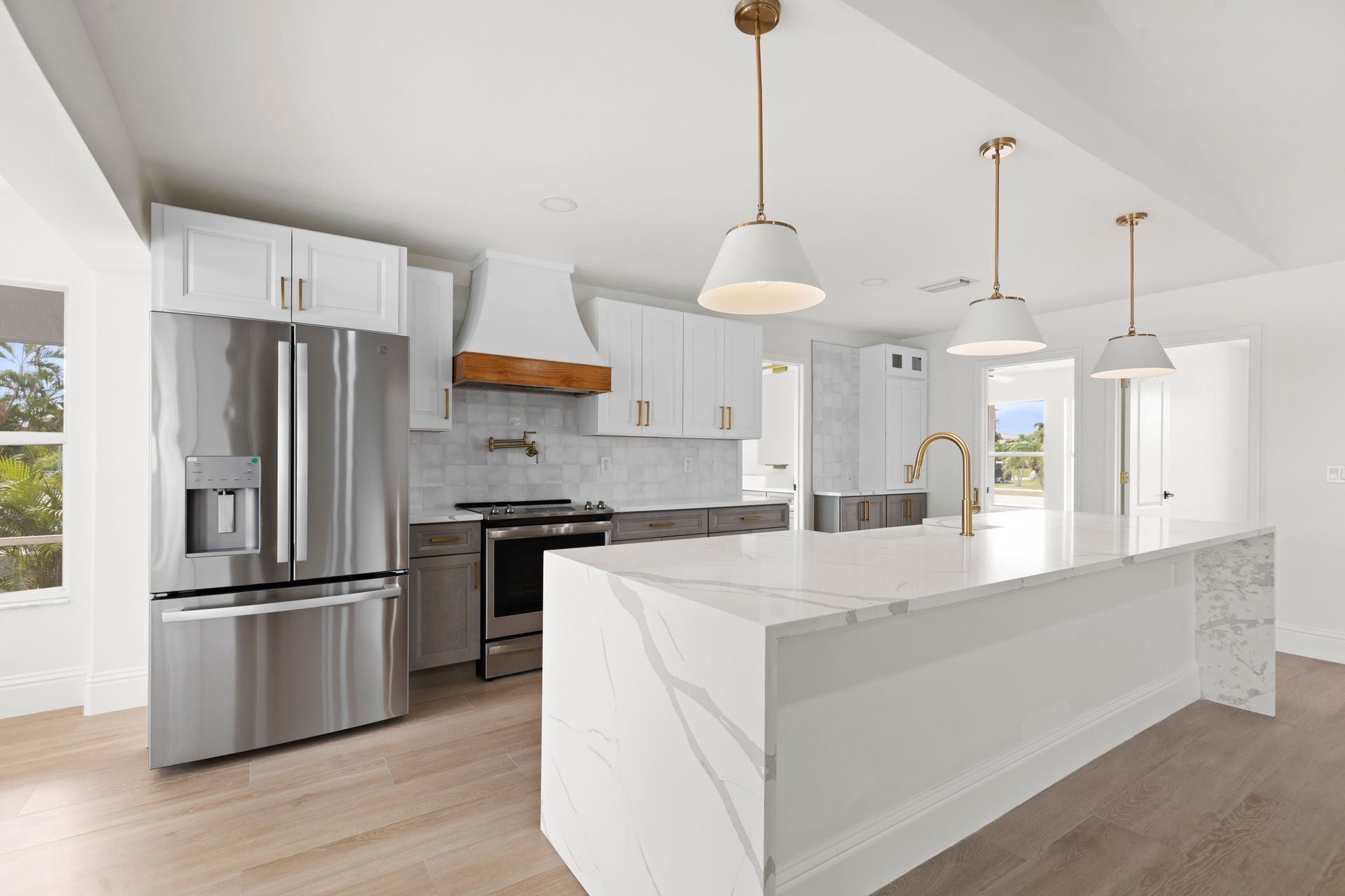 A kitchen with white cabinets , stainless steel appliances , and a large island.