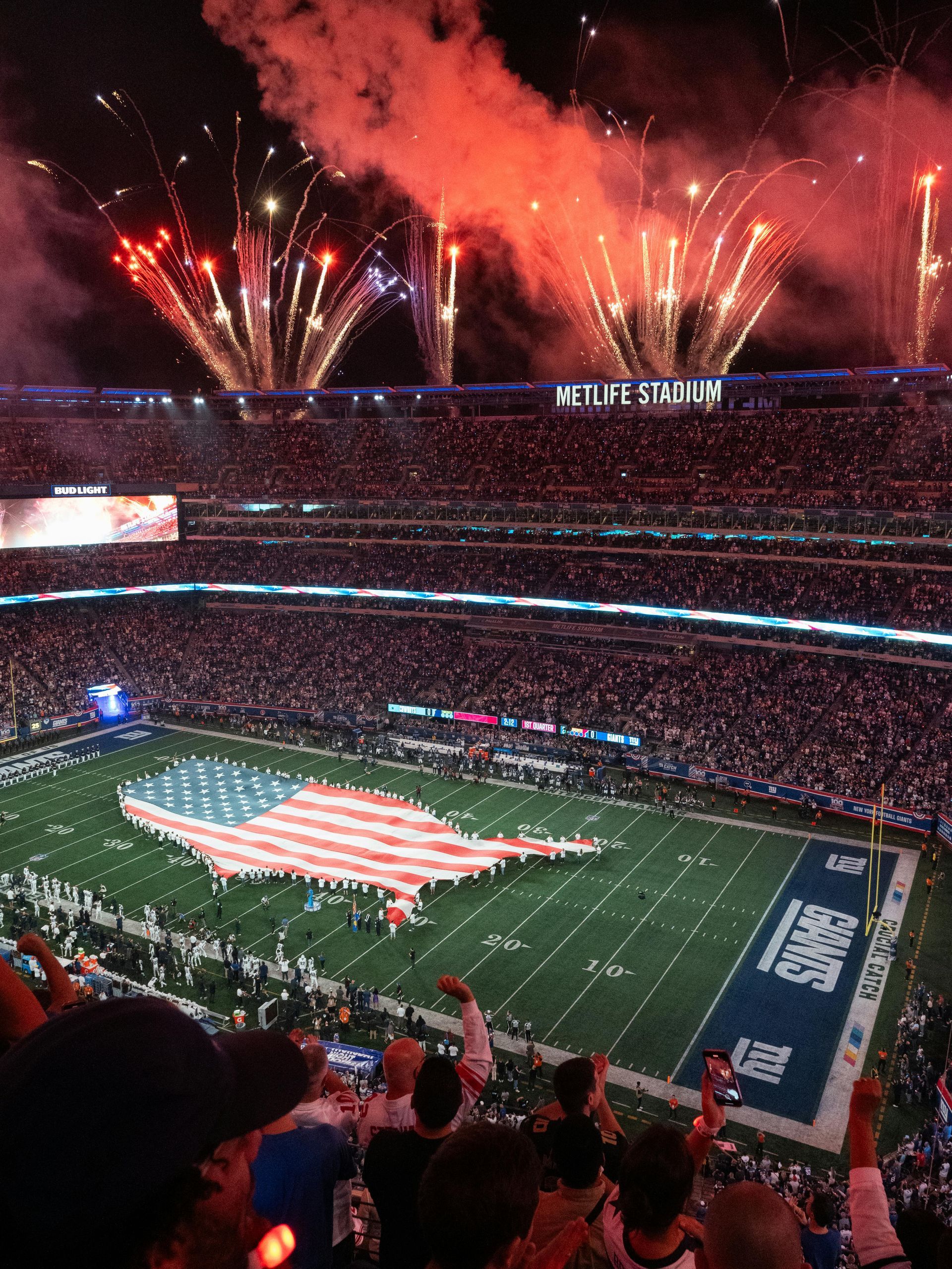 Fireworks are displayed over a football field at night