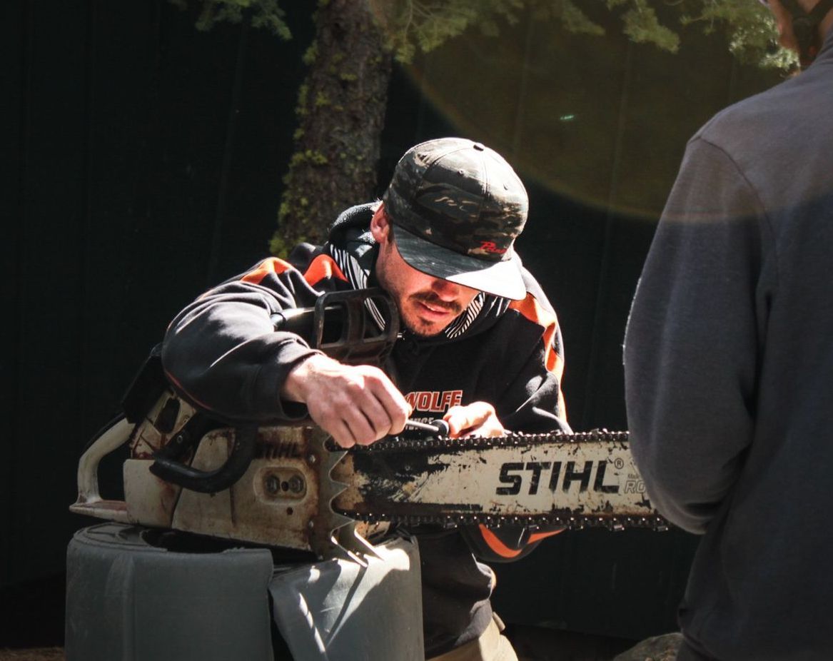 A man is cutting a tree branch with a chainsaw.
