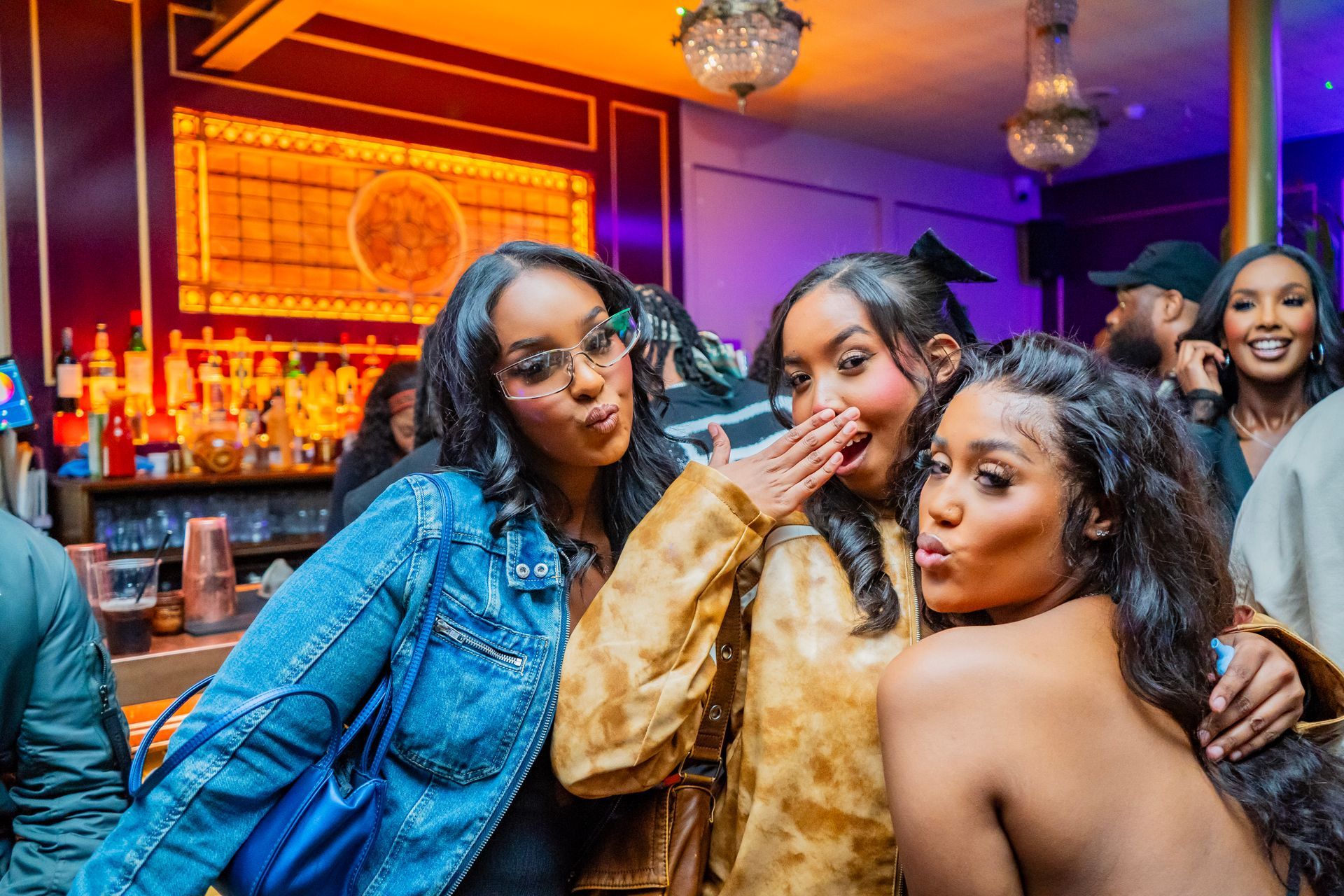 Three women are posing for a picture in a bar.
