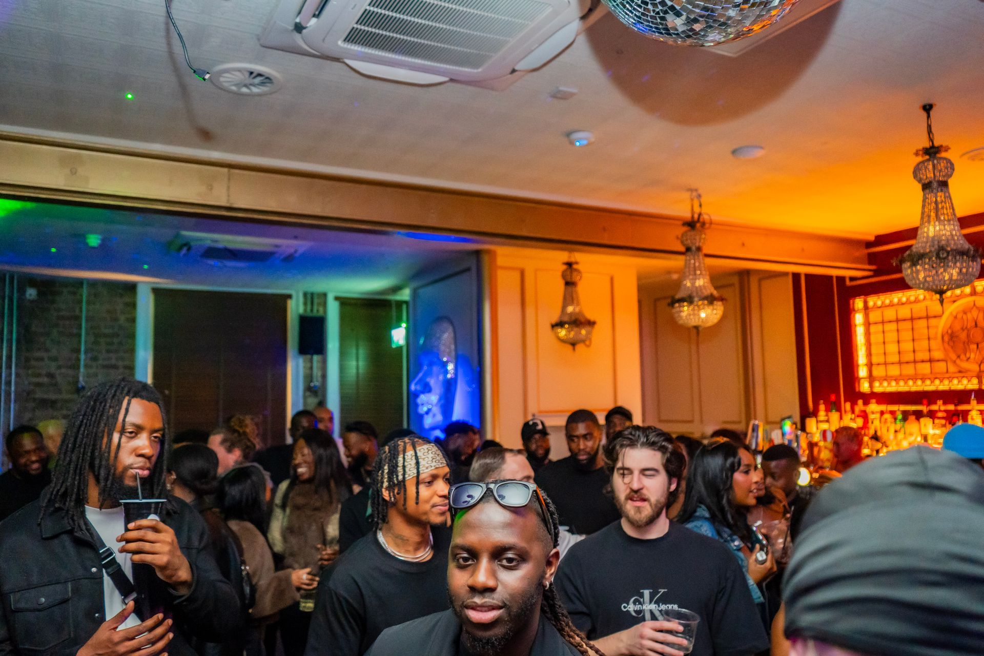 A group of people are standing in a room with a disco ball on the ceiling.
