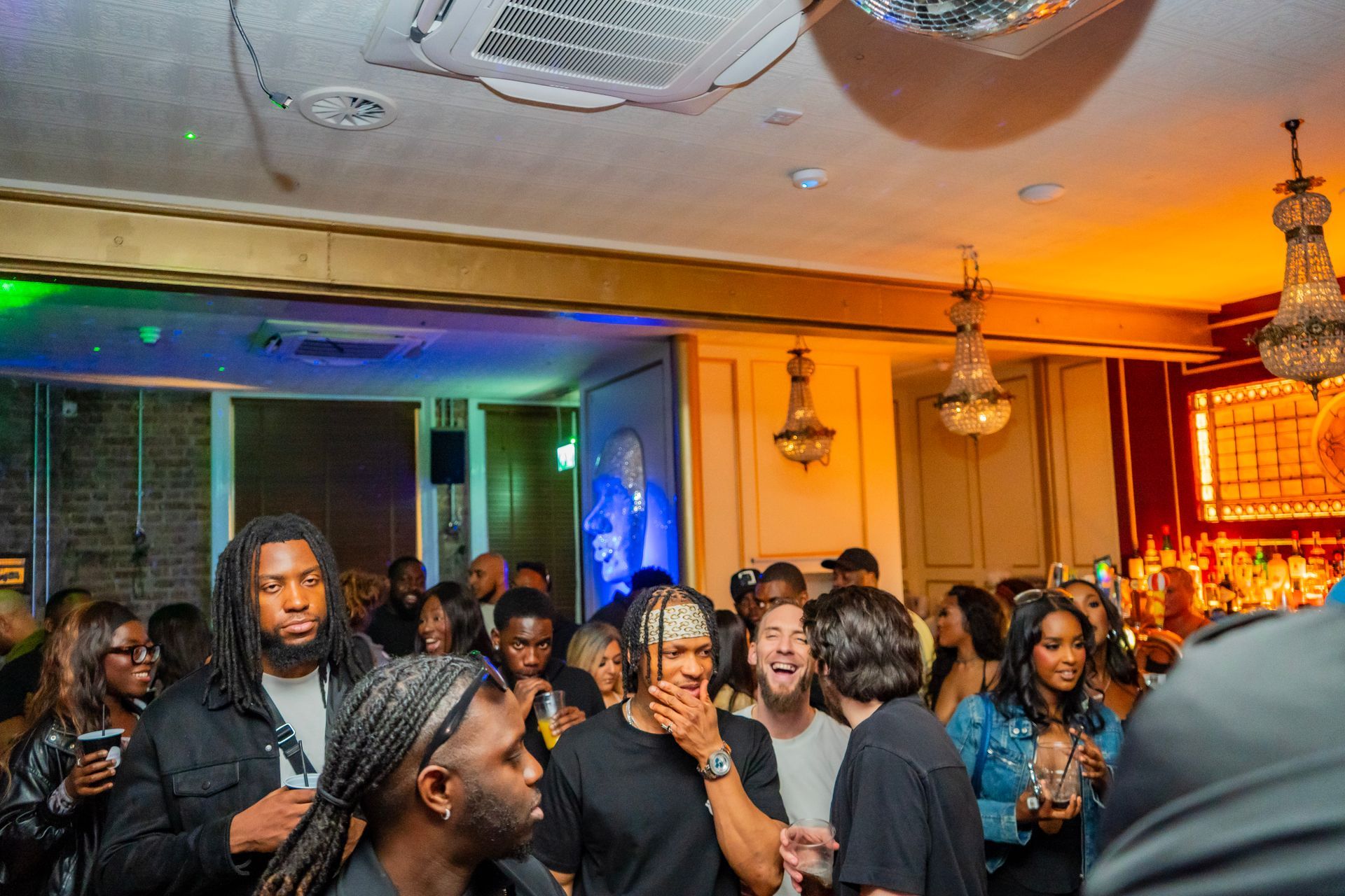 A group of people are standing in a room with a disco ball hanging from the ceiling.
