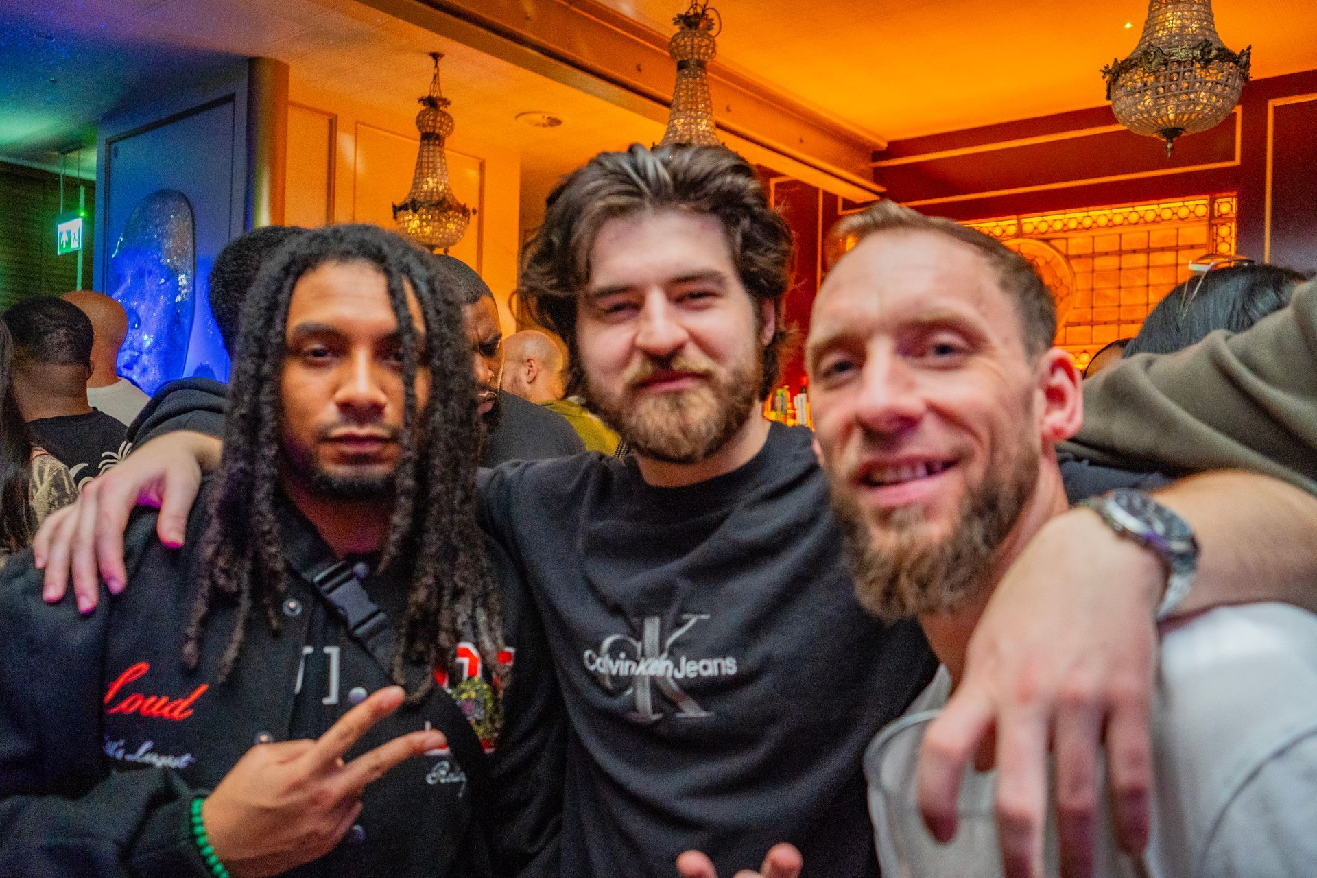 Three men are posing for a picture together in a club.