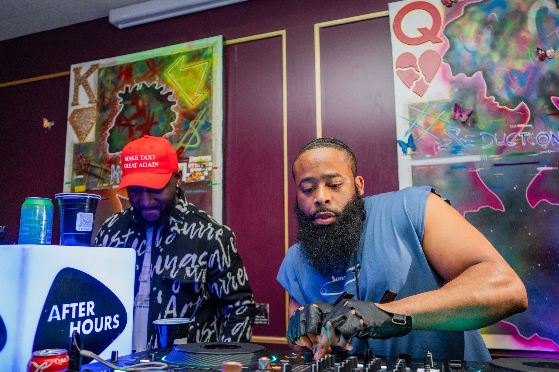 A man with a beard is playing a dj set in a room.