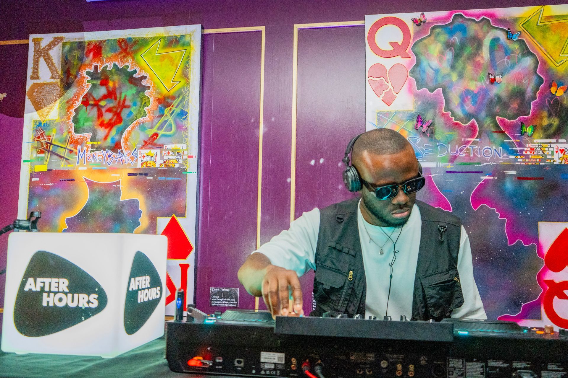 A man wearing headphones and sunglasses is playing music on a turntable.