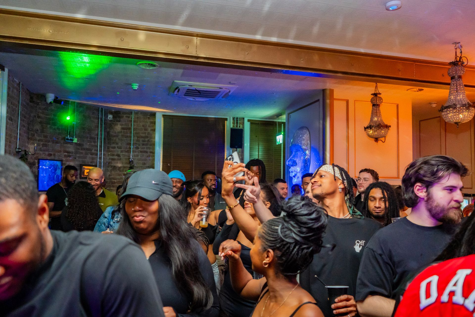 A crowd of people are standing in a room taking pictures of each other.