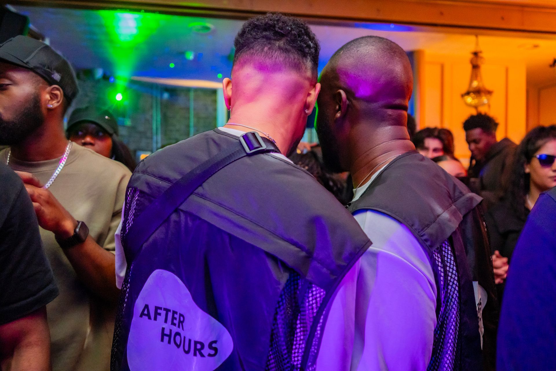 Two men are standing next to each other in a crowd of people at a party.