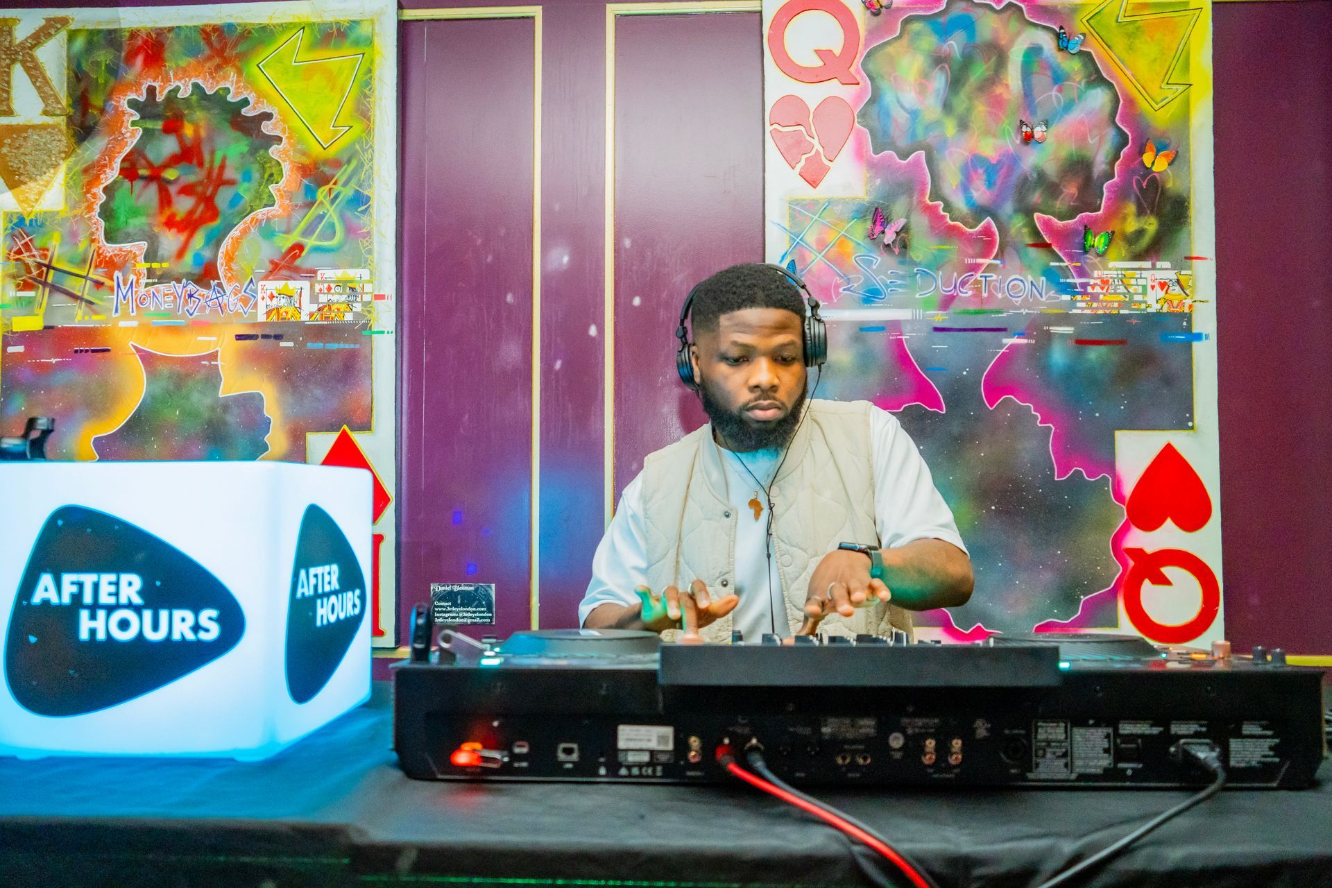 A man wearing headphones is playing music on a mixer.