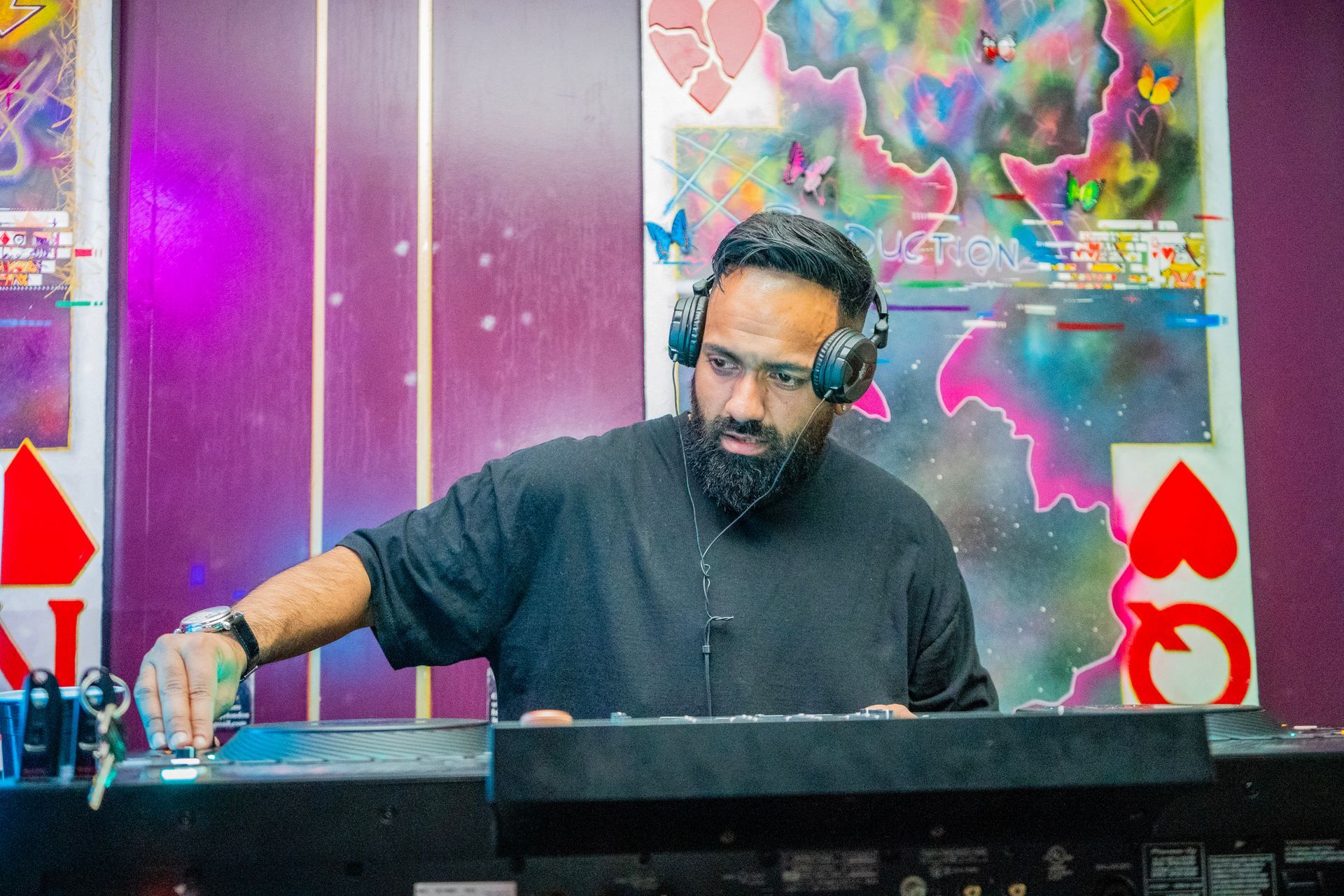 A man with a beard is wearing headphones and playing a dj set.