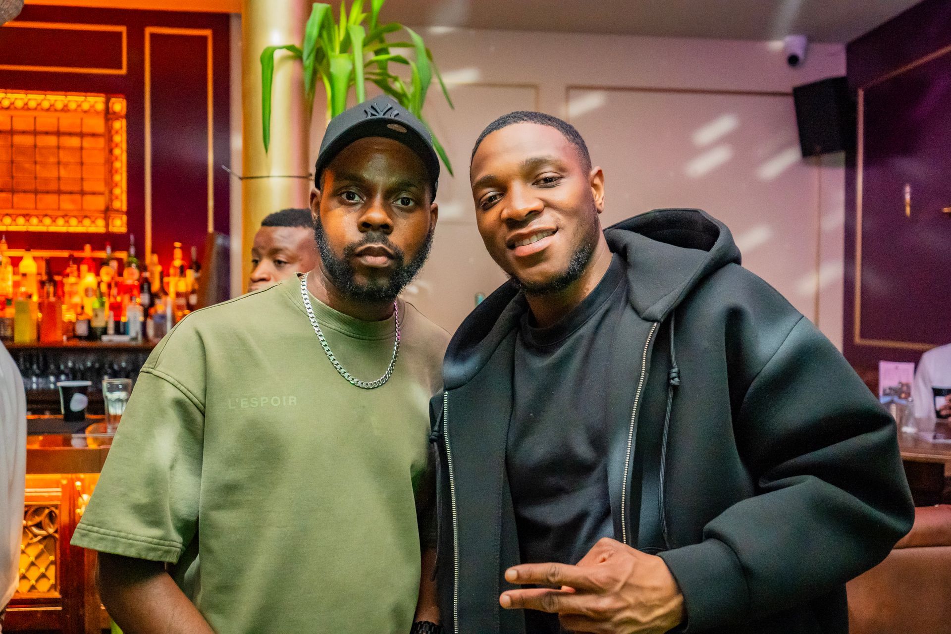 Two men are posing for a picture together in a bar.