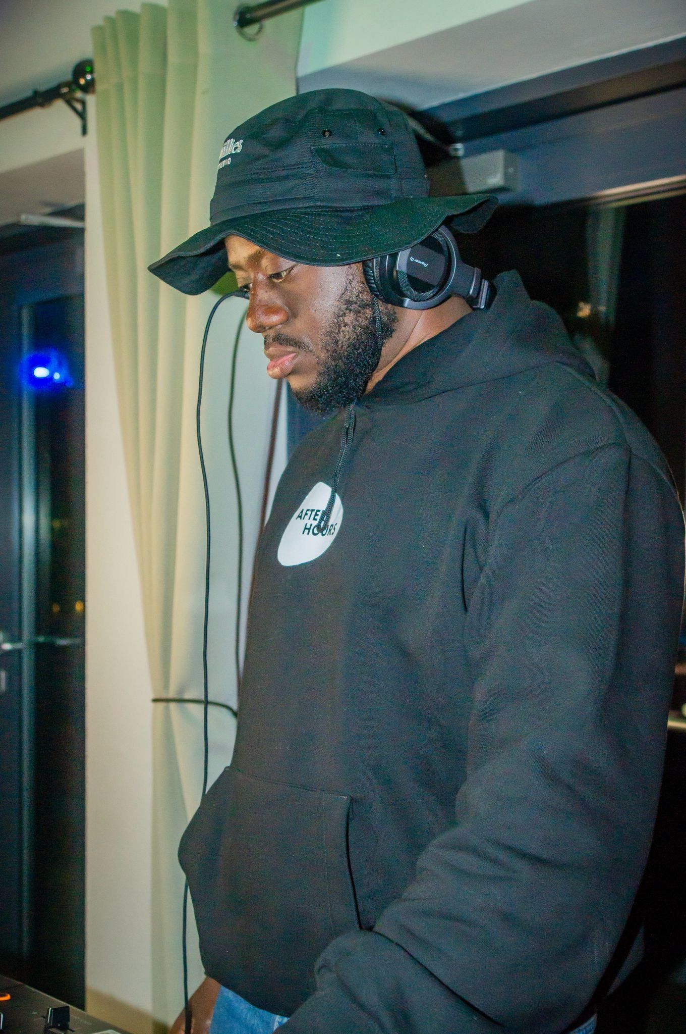 A man wearing headphones and a hat is playing music.