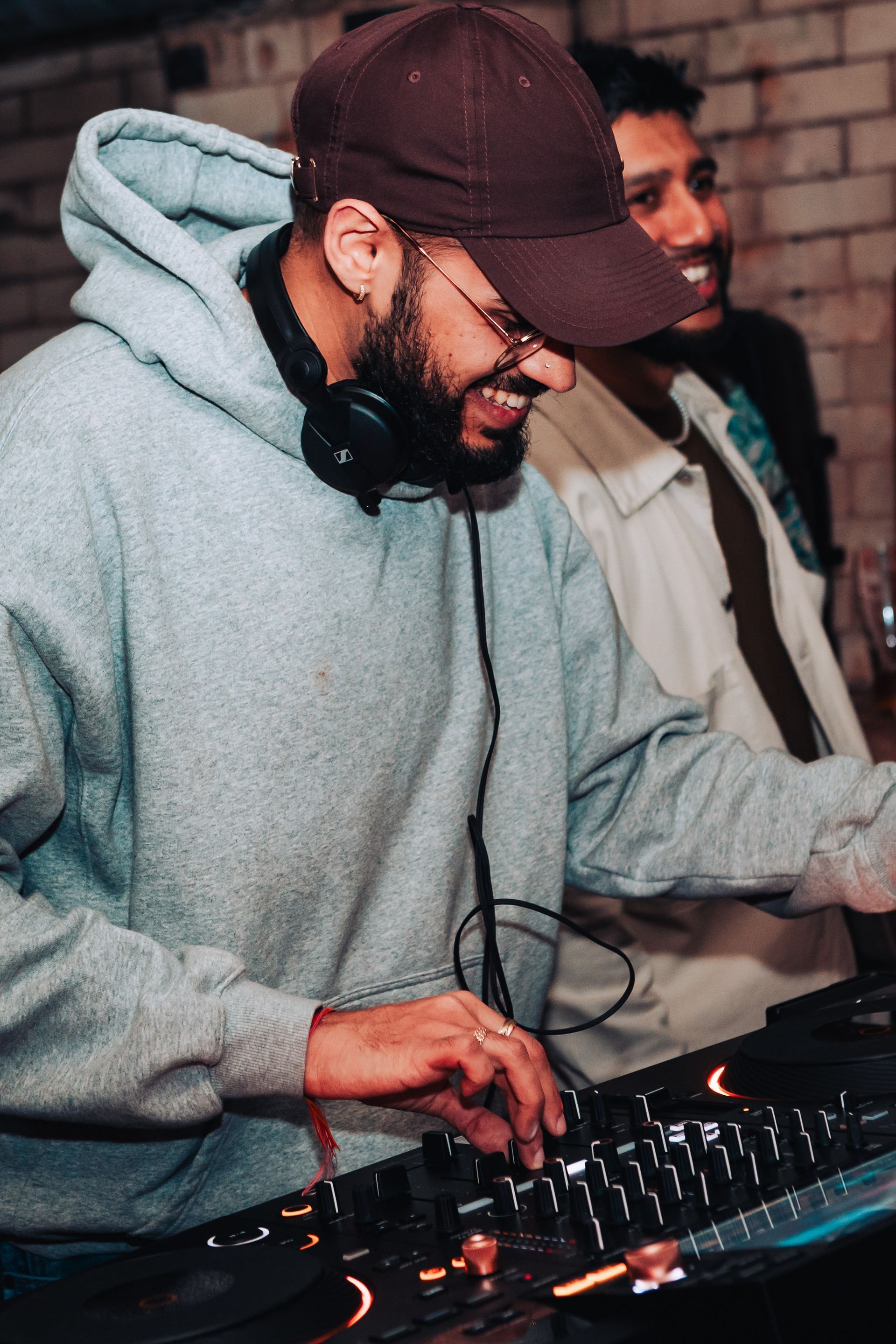 A man wearing headphones and a hat is playing music on a mixer.