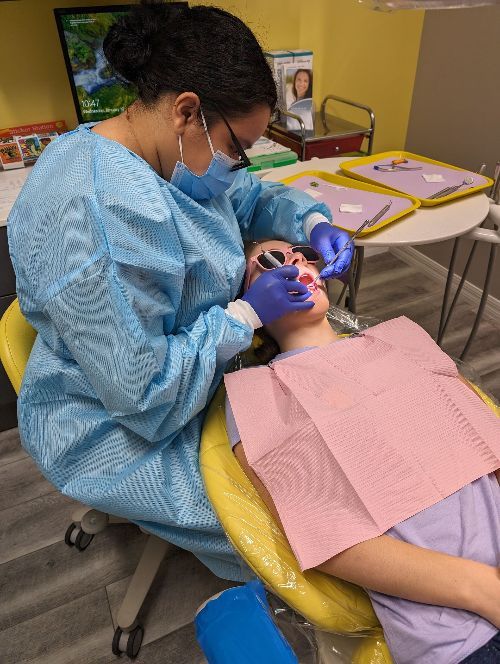 A dentist is examining a child 's teeth in a dental chair-Dental Studio 4 Kids-Lust FL