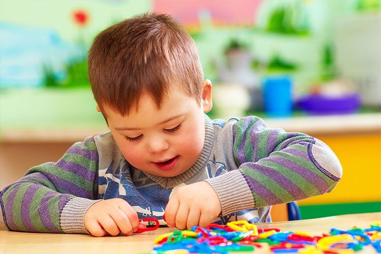 Images of young child with Down syndrome playing with toys - Dental Studio 4 Kids Lutz Florida