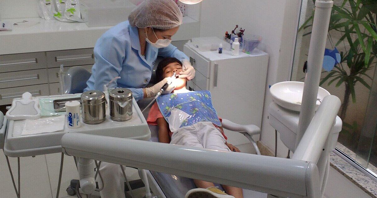 A woman is examining a child 's teeth in a dental office.