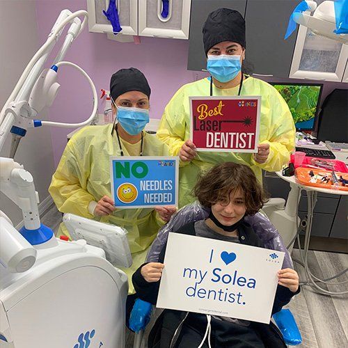 A boy is sitting in a dental chair holding a sign that says `` i love my solea dentist ''.