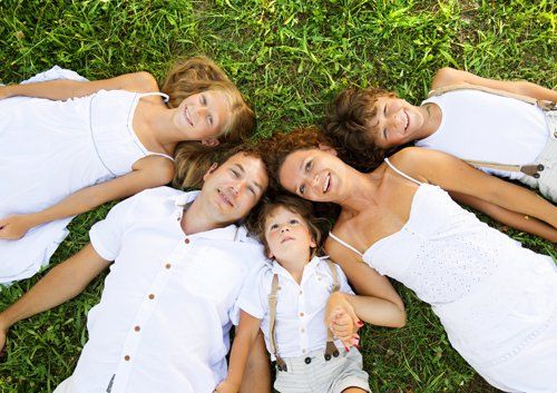family laying on grass smiling