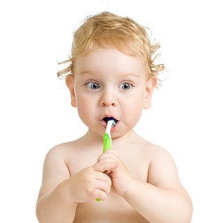 baby holding toothbrush in mouth