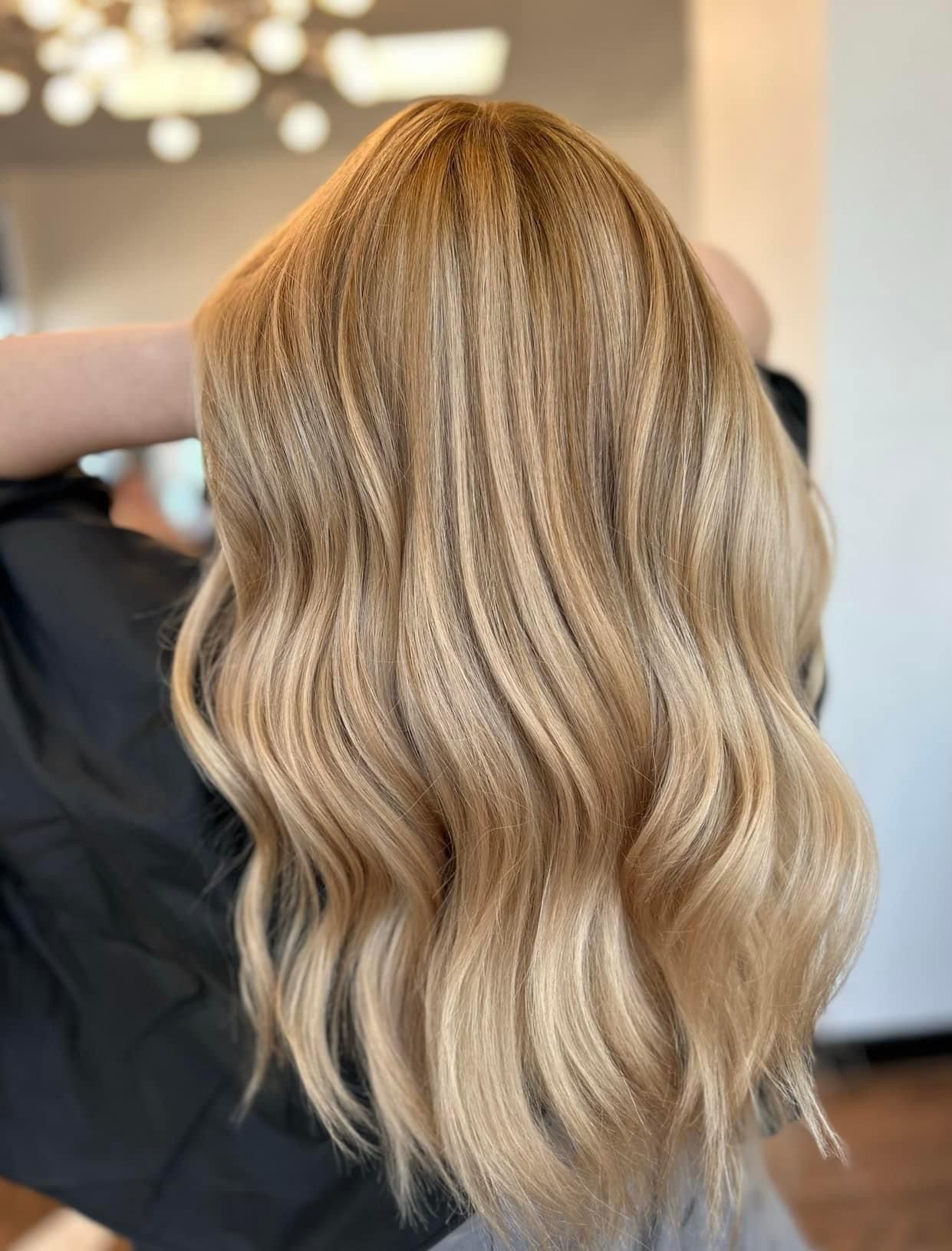 Blonde, wavy hair with highlights; hands touching hair.