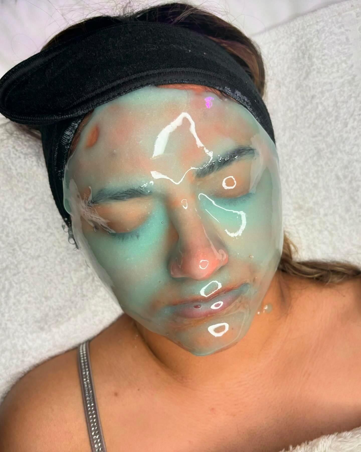 Person wearing a teal facial mask, lying down. Black headband, white towel, eyes closed.