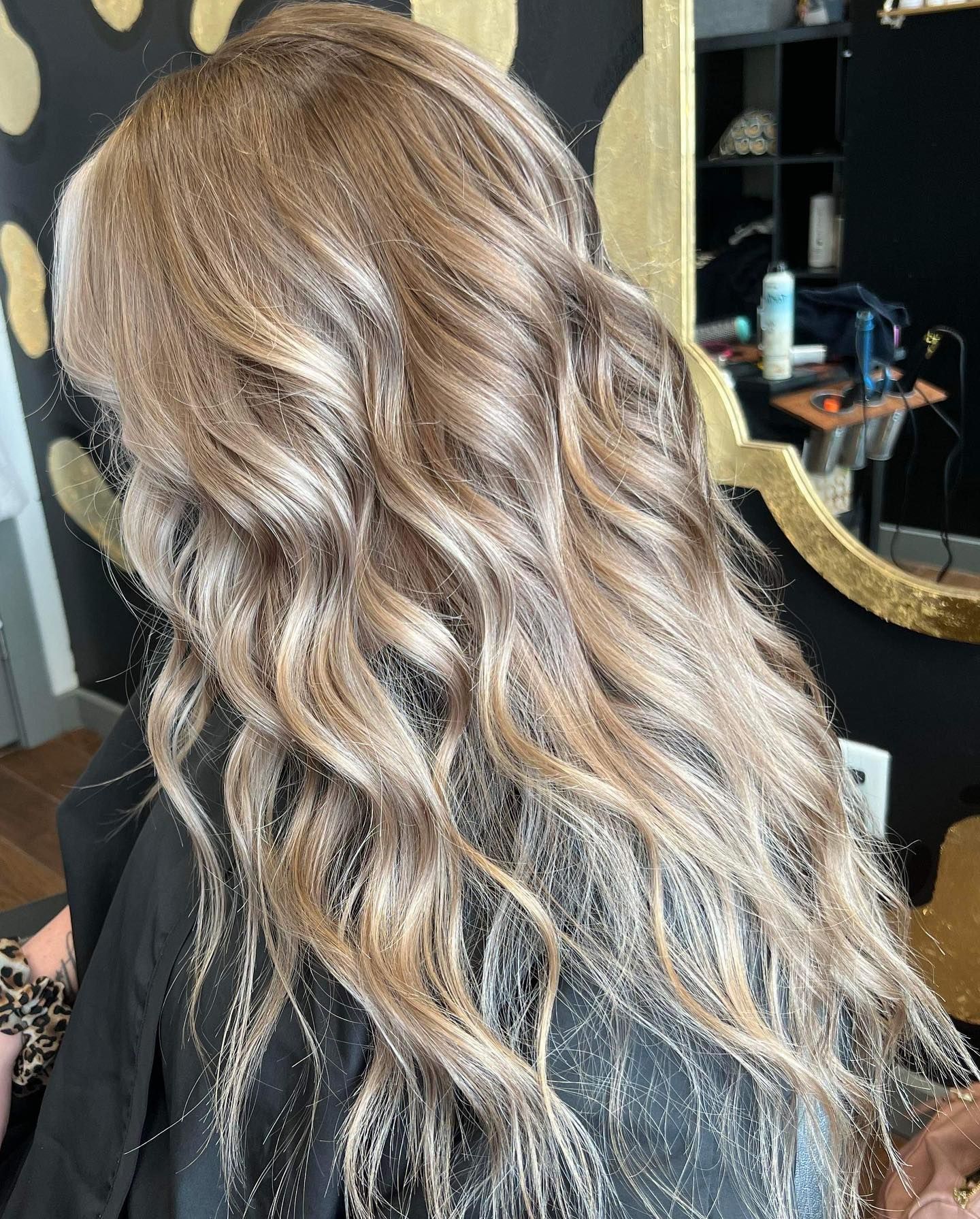 Wavy, long ash blonde hair with highlights in a salon setting.