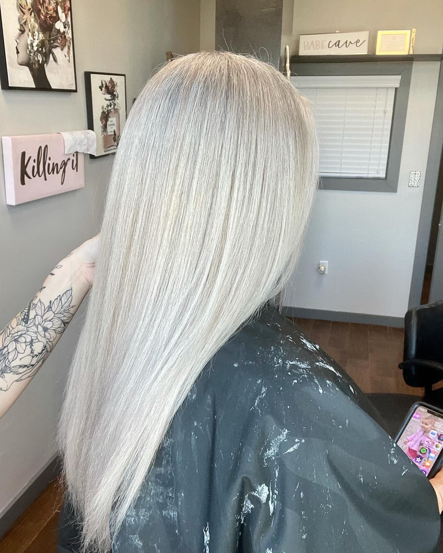 Person with straight, light-colored hair in a salon. Hair is coated with a bleaching product.