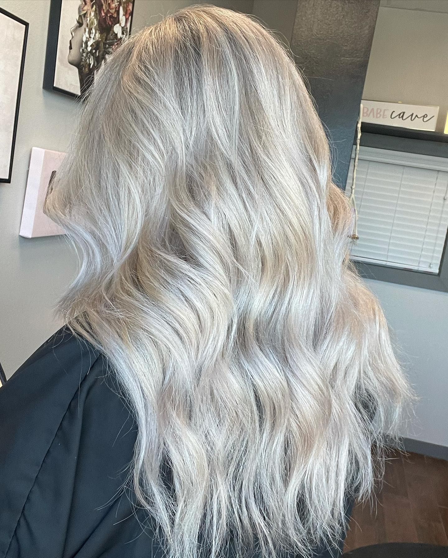 Woman with long, wavy, ash blonde hair in a salon setting.