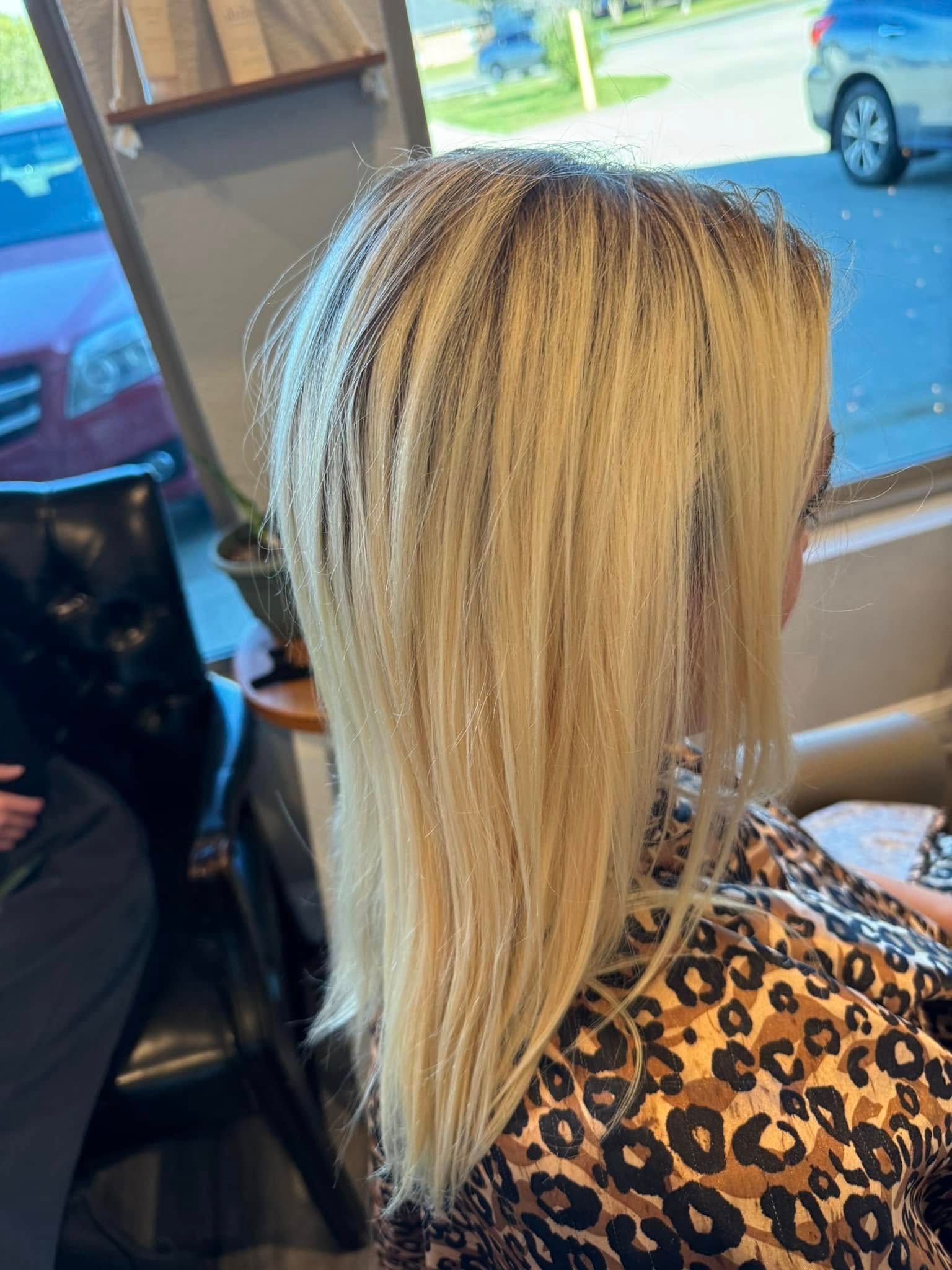 Blonde hair on a person, inside a salon, facing a window. The person is wearing a leopard print top.