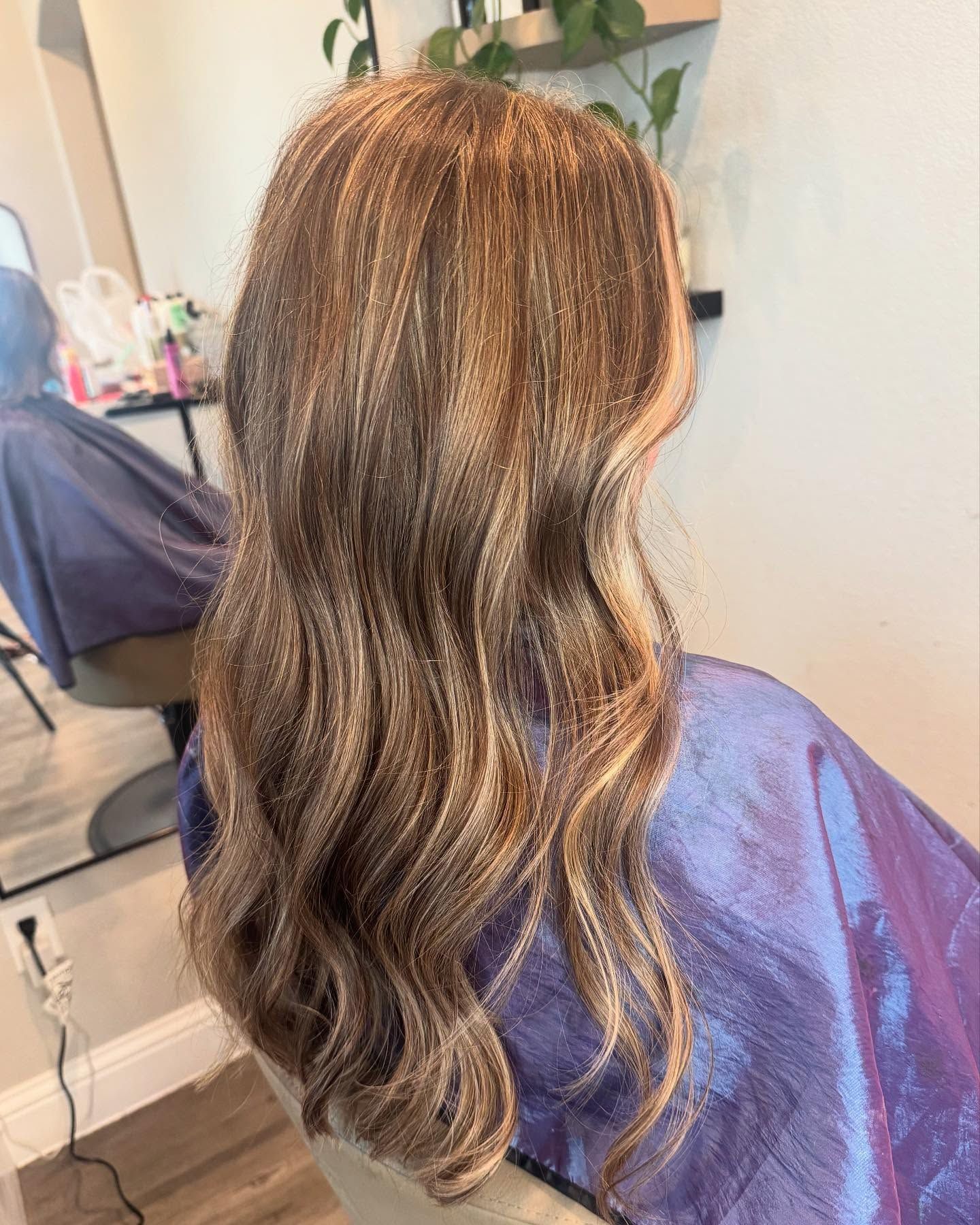 Hair with blonde highlights, styled in loose waves, in a salon setting.
