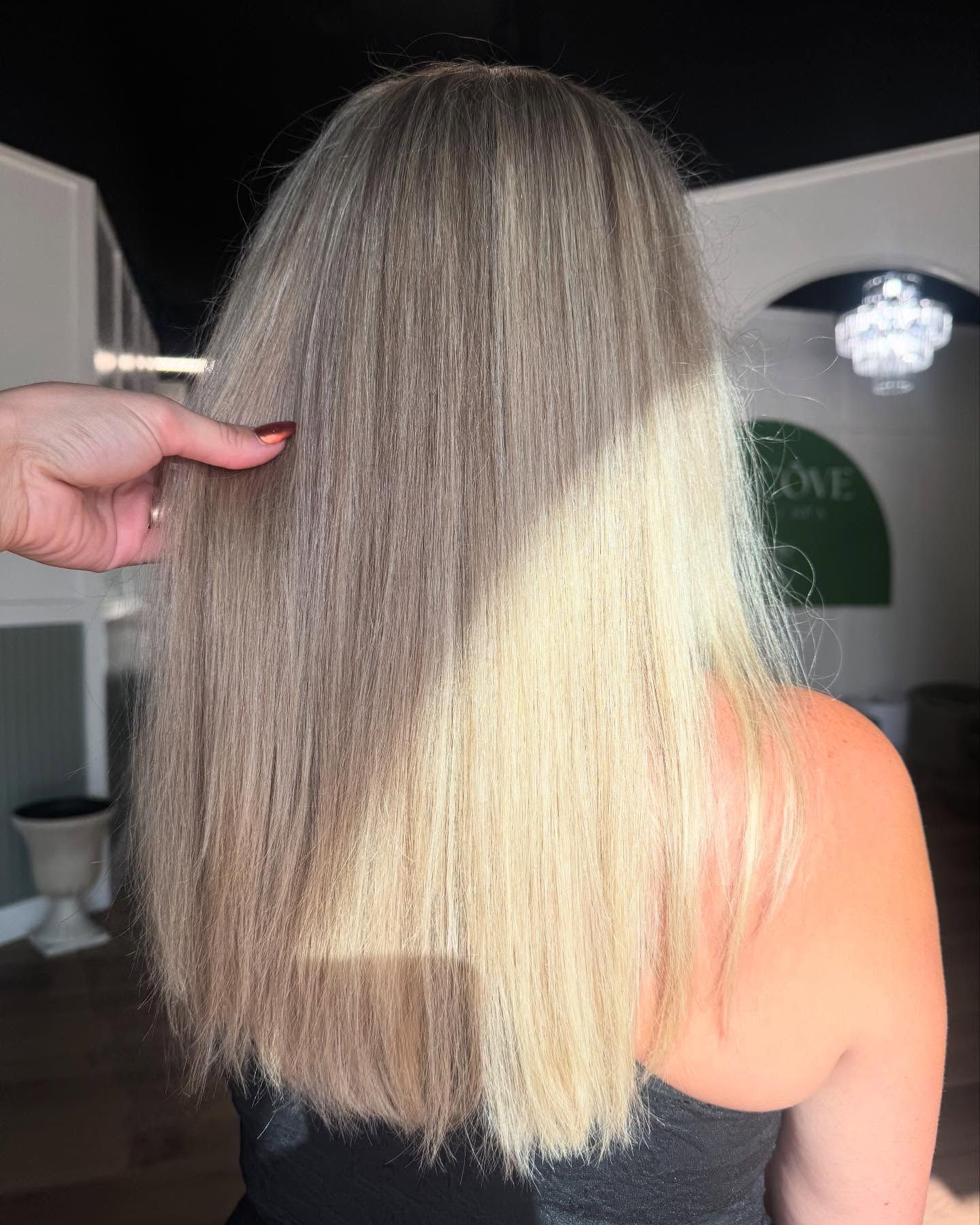 Blonde and brown layered hair being held by a hand; lit by sunlight.