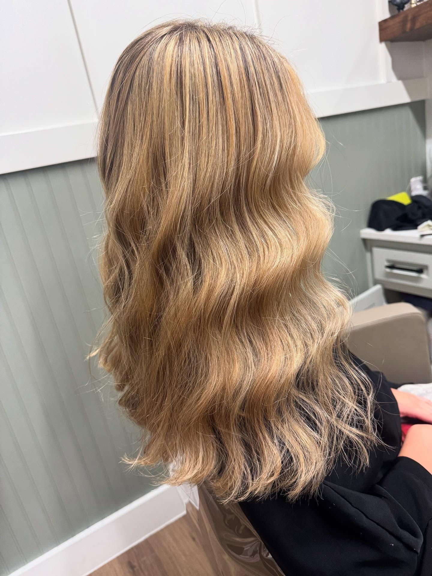 Blonde hair with wave style, sitting in a chair, inside a salon.