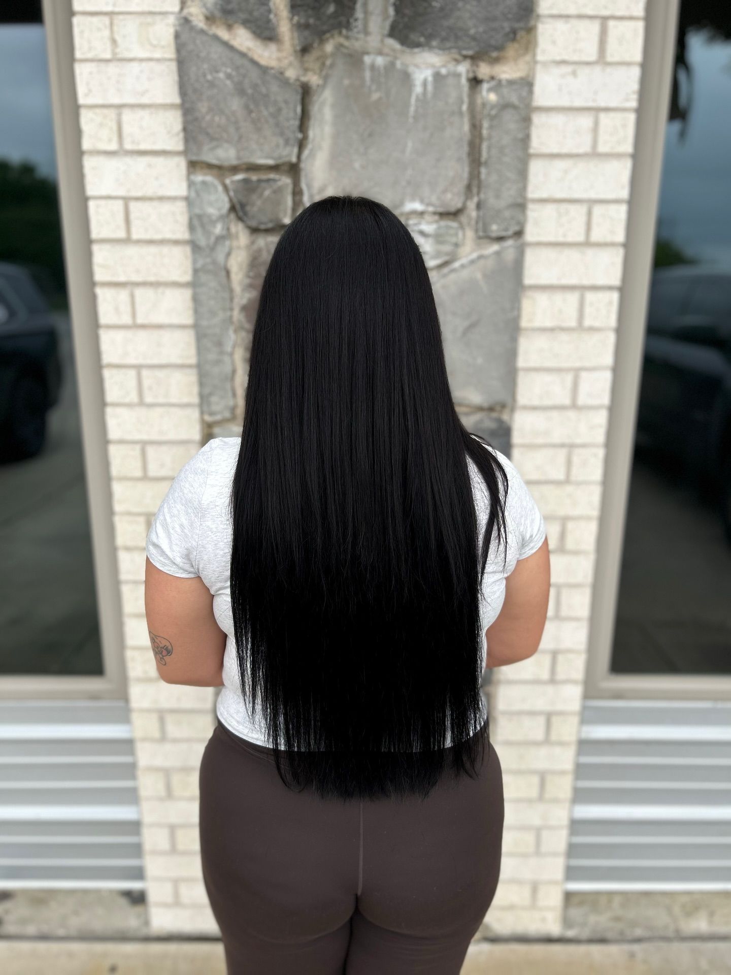 Person with long, black hair stands facing away from the camera.