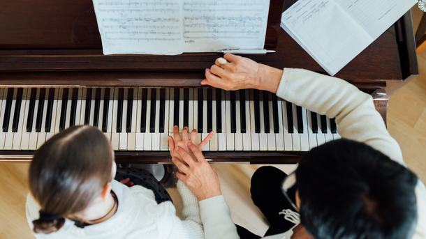 Un homme et une petite fille jouent du piano ensemble.
