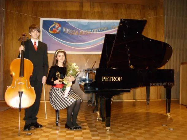 Un garçon et une fille se tiennent devant un piano pétrof
