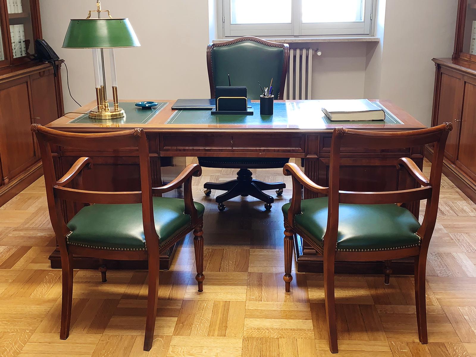 Una scrivania di legno con sedie verdi e una lampada verde