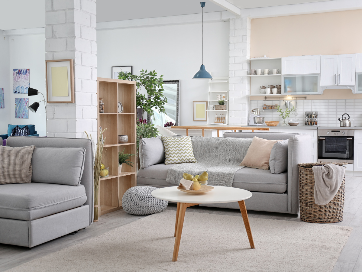 Bright, cozy living room with gray sofas, a round coffee table, and open shelving in a white interior