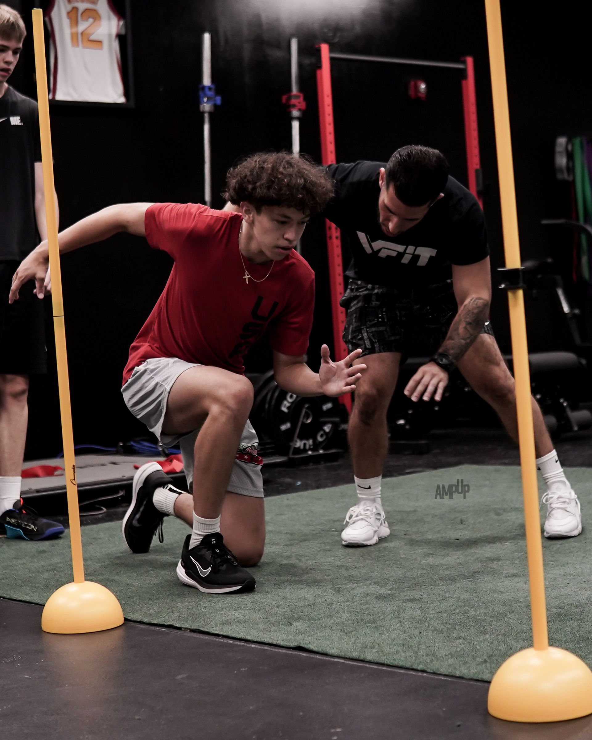 A man in a red shirt is kneeling down next to a man in a black shirt.