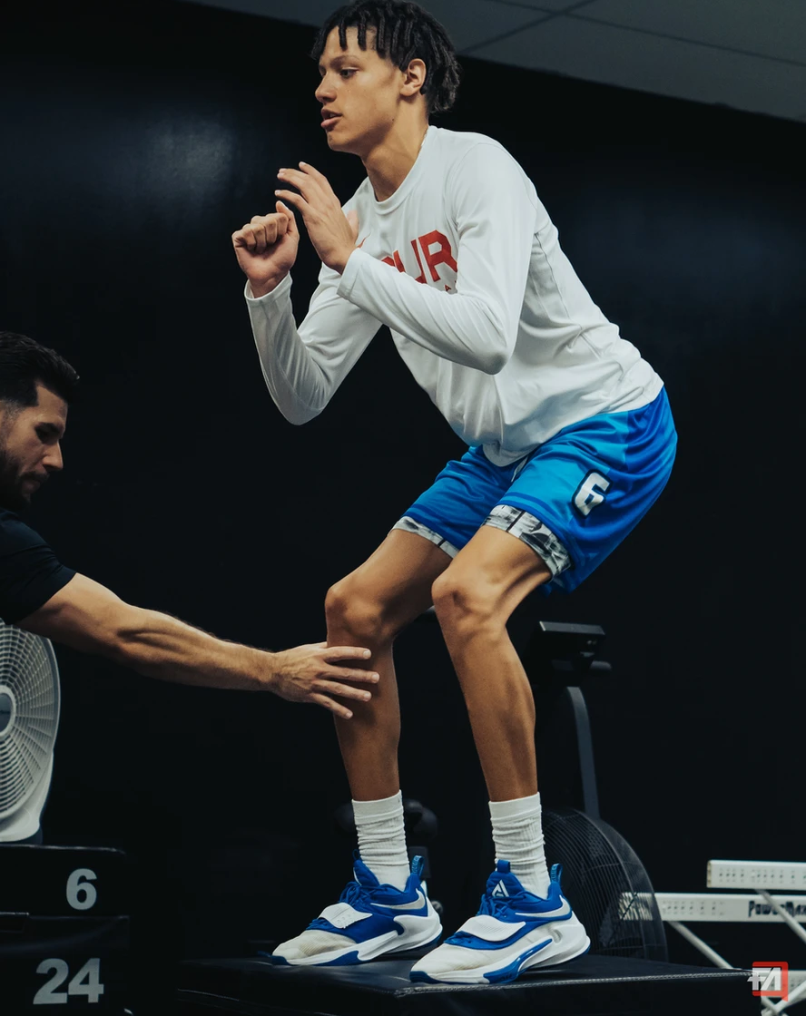 A man is helping a young man jump on a treadmill.