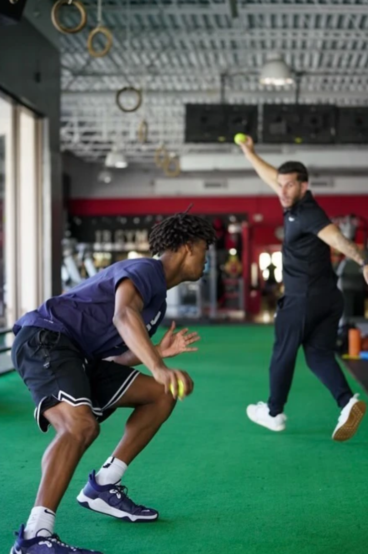 A man is throwing a ball to another man in a gym