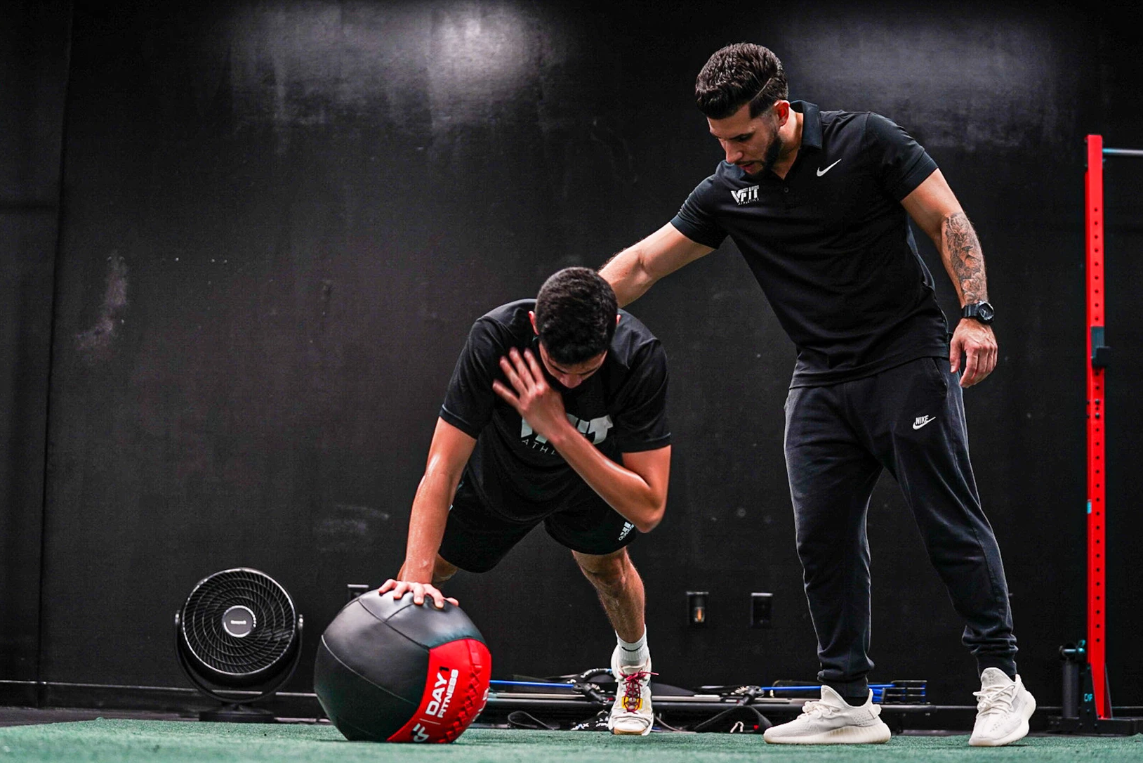 Two men are doing push ups with a medicine ball in a gym.