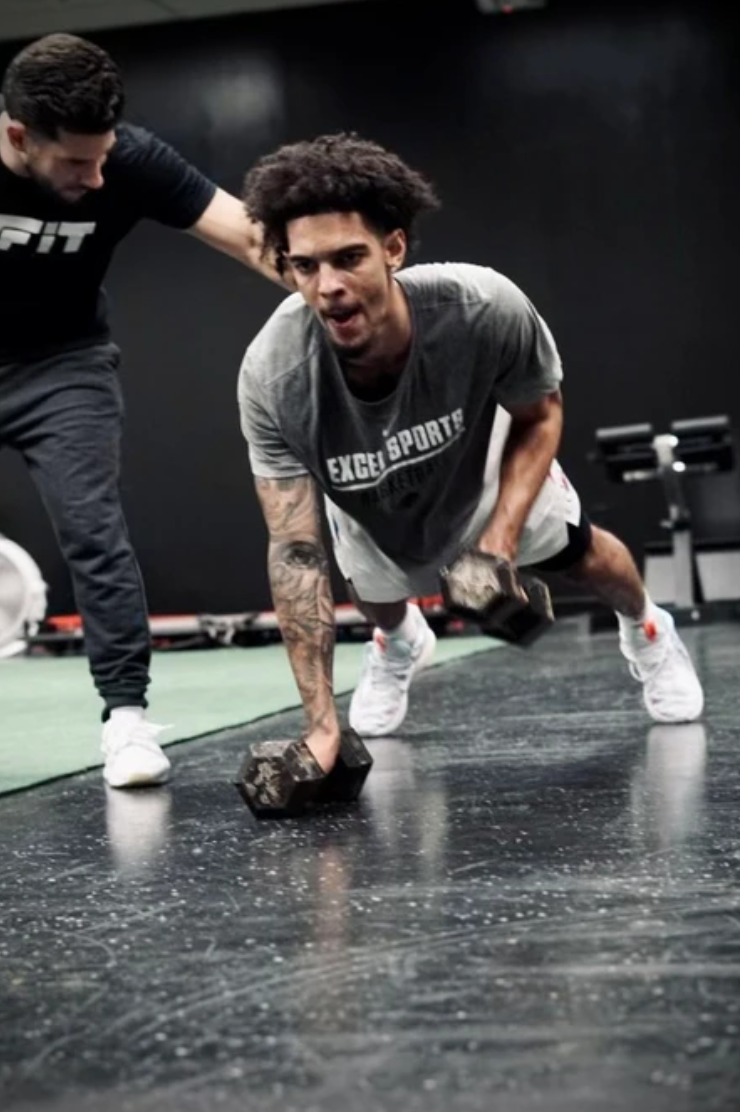 A man is doing push ups with a dumbbell in a gym.
