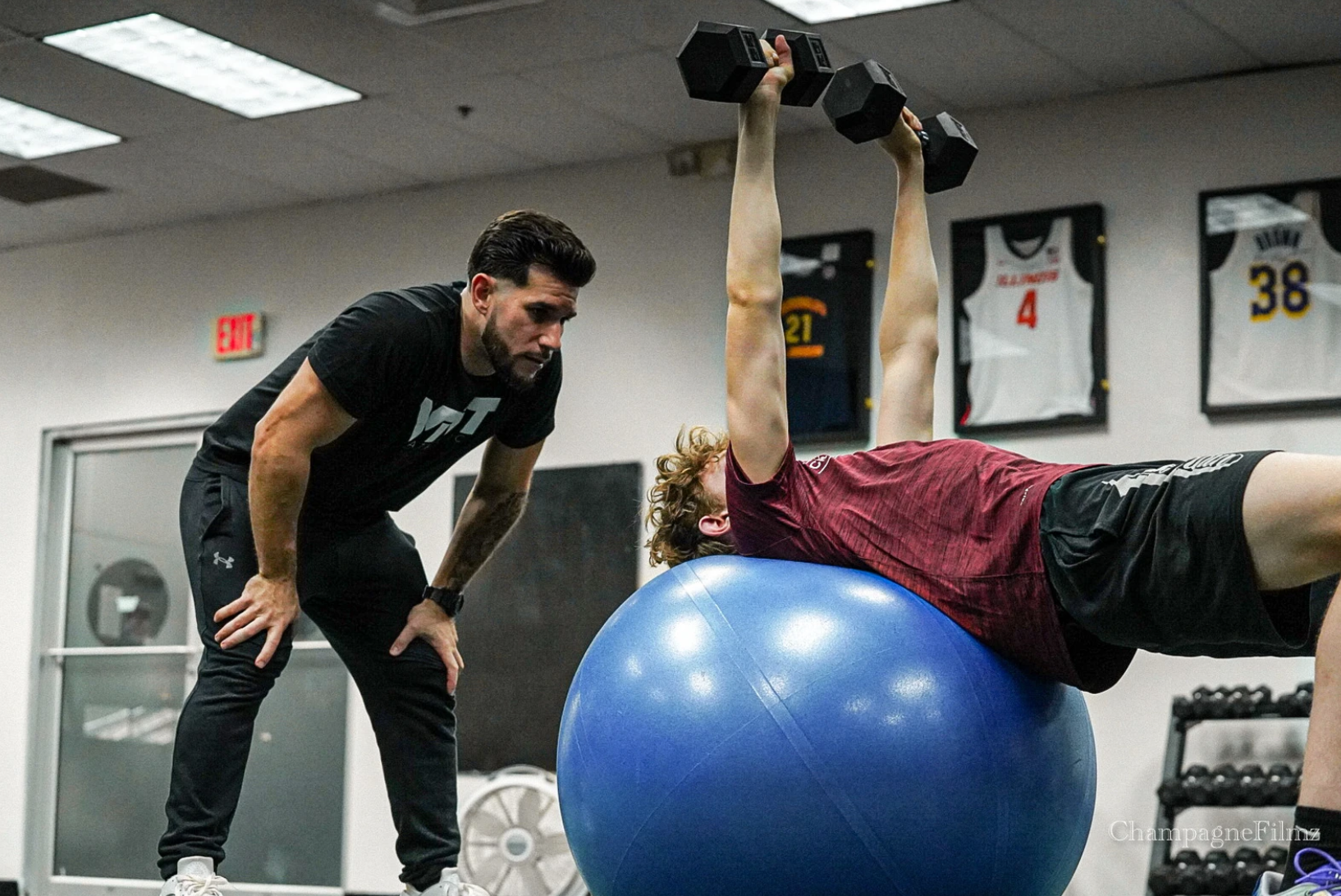 A man is lifting dumbbells while laying on an exercise ball.