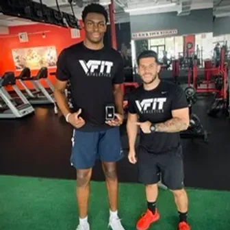 Two men are standing next to each other in a gym wearing vfit shirts.