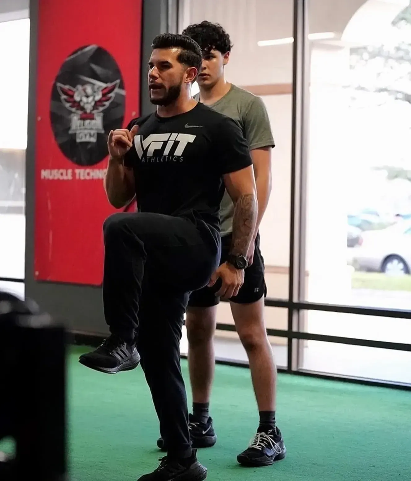 A man wearing a vfit shirt is doing squats in a gym