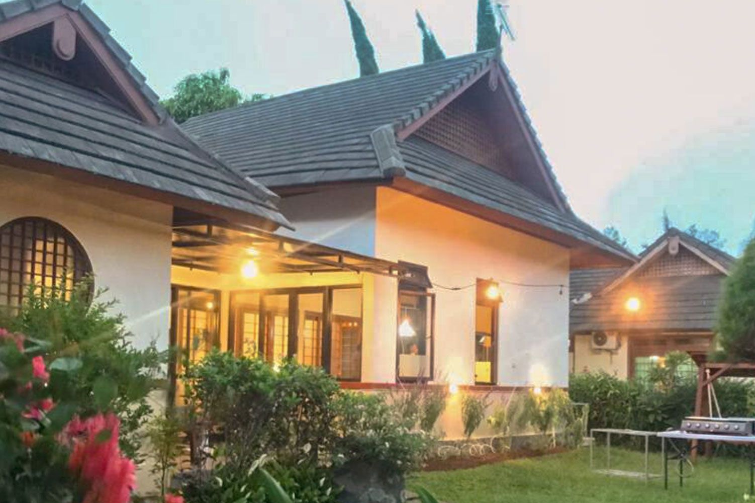 Buildings with brown roofs, outdoor lighting, and green yard in a dusk setting.