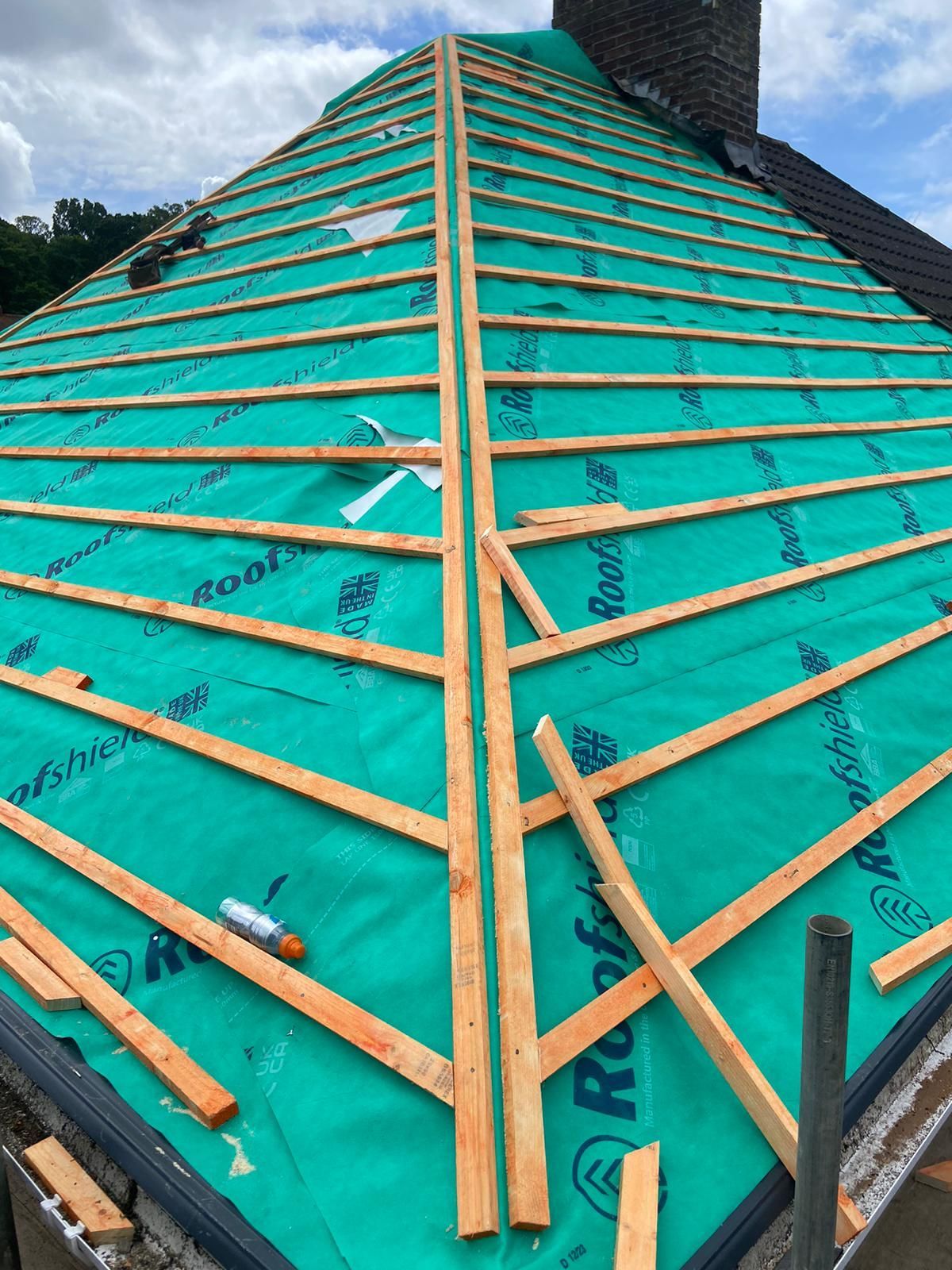 A roof is being built with green roofing material and wooden beams.