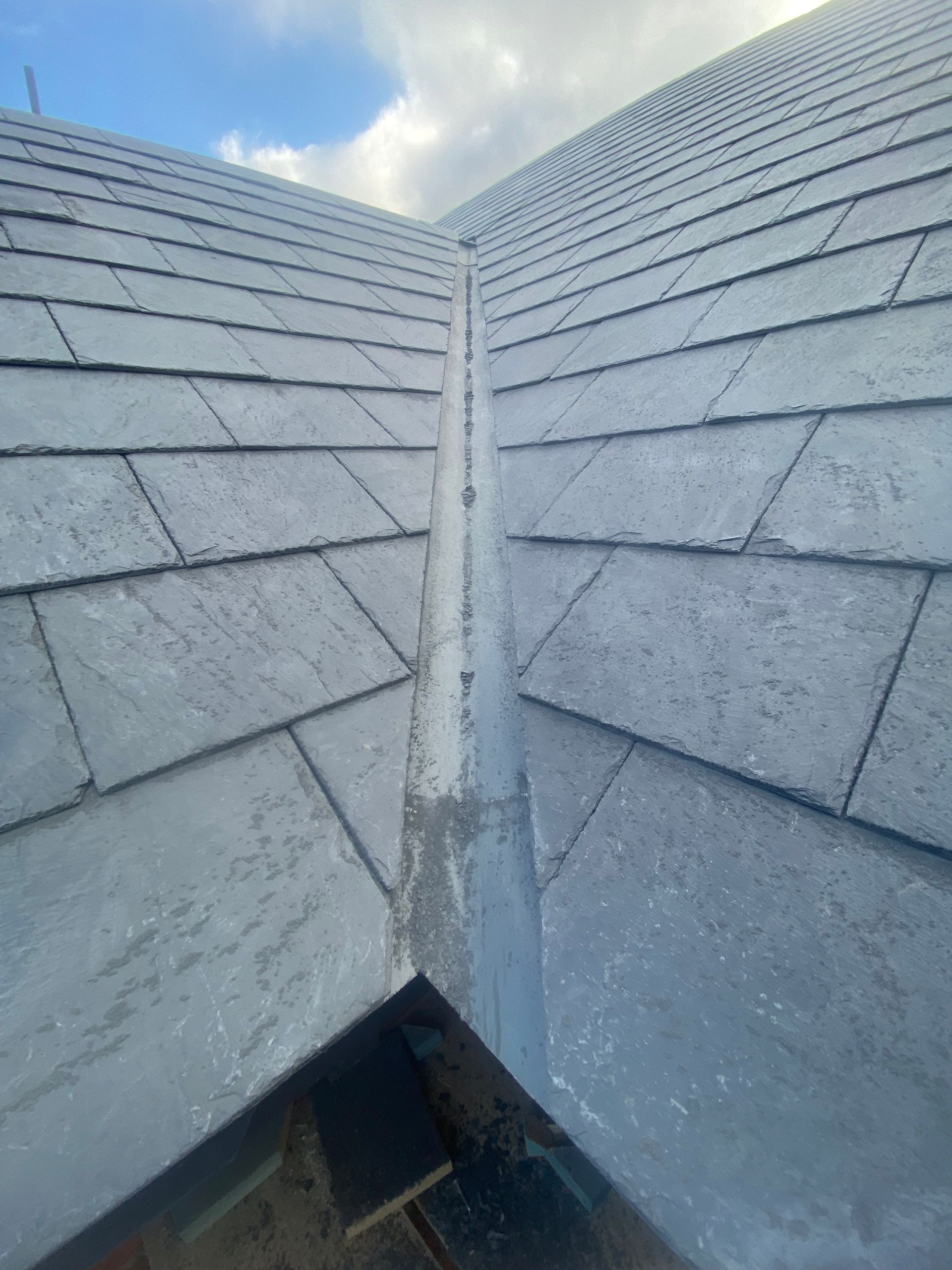 A close up of a slate roof with a gutter on it.