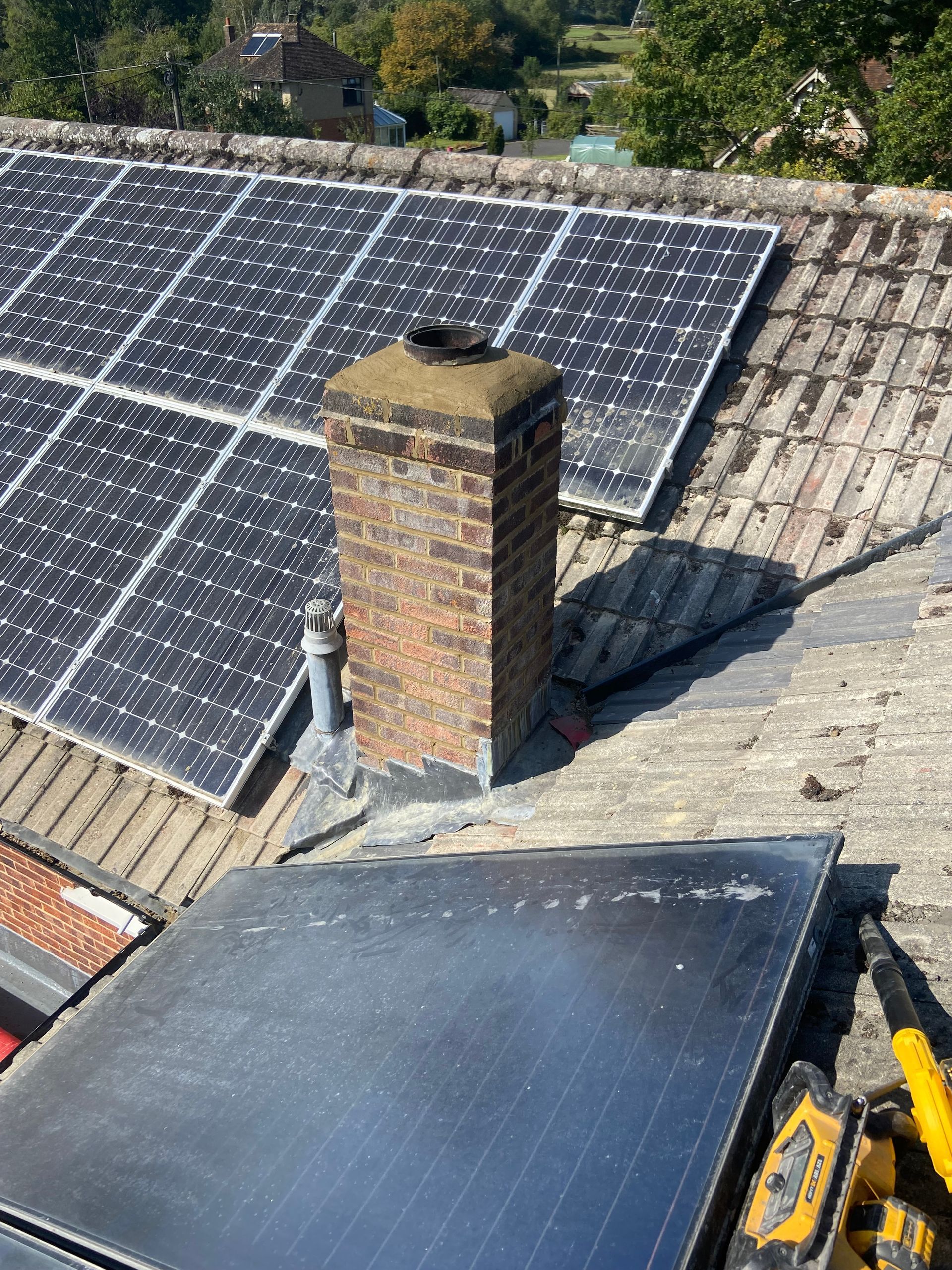 A roof with solar panels and a chimney on it.