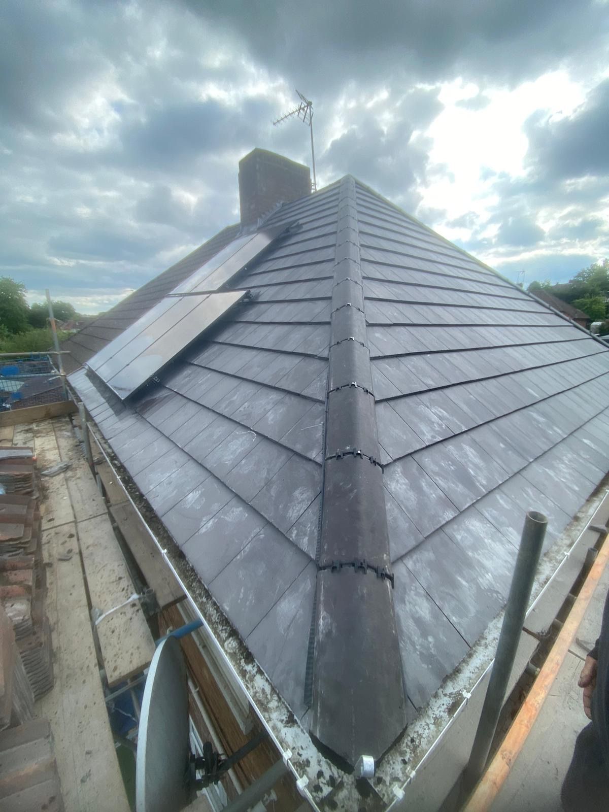 A roof with a chimney and solar panels on it.